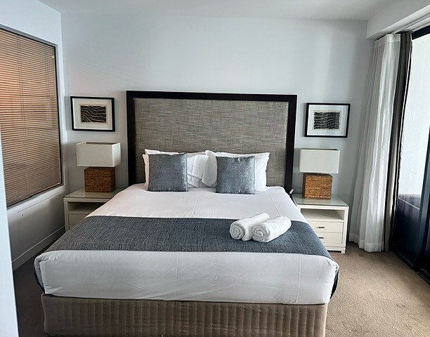 Queen bed freshly made with rolled towels, ready for the next guest